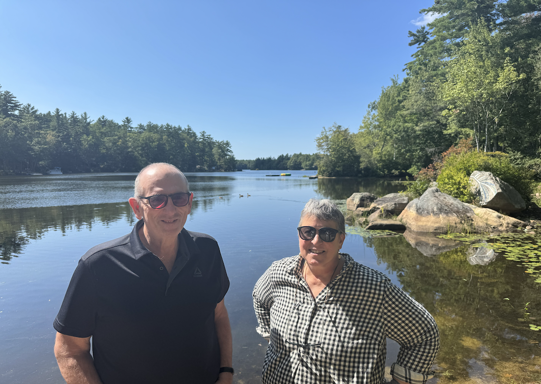 Ernie Creveling and Lisa Murphy smile and stand in front of Swains Lake in Barrington, NH