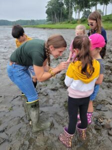 Young woman interacting with children on a mud flat.