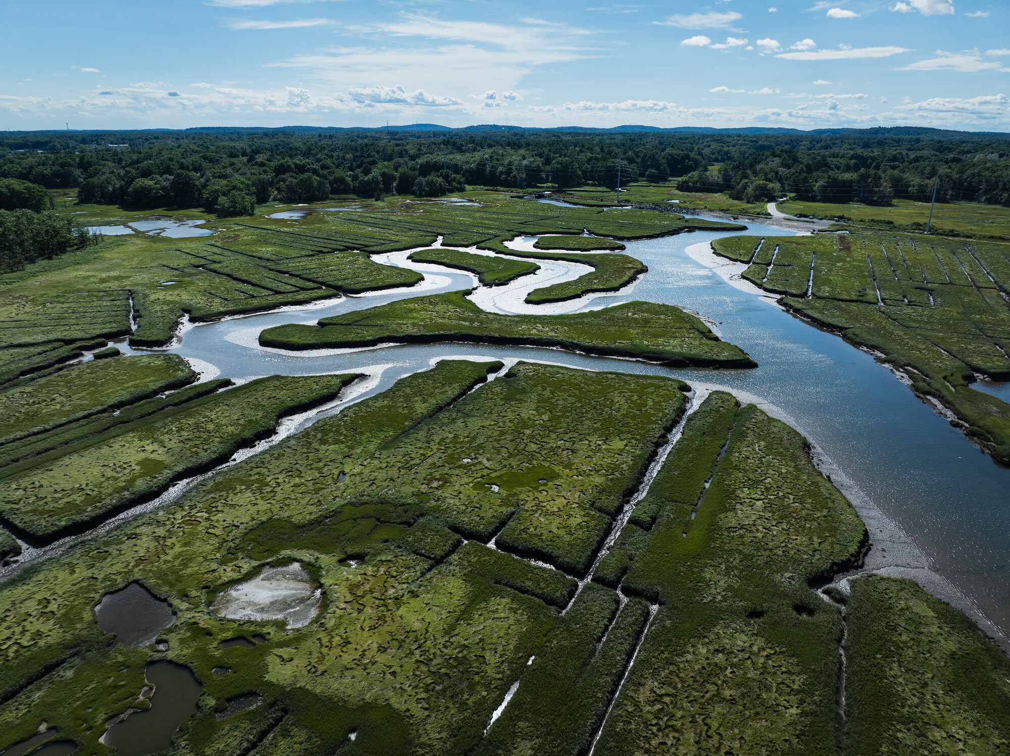 An aerial view of the Hampton Seabrook Estuary in summer, with the upper watershed and NH hills in the background.